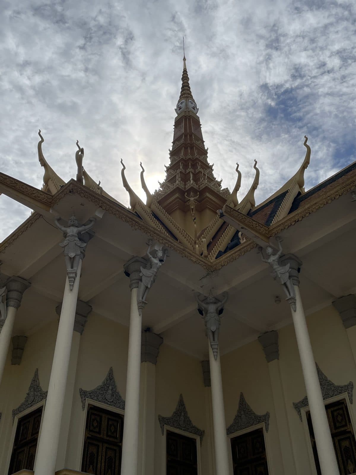 The gilded spire of the Silver Pagoda at Phnom Penh's Royal Palace, seen from below against a cloudy sky